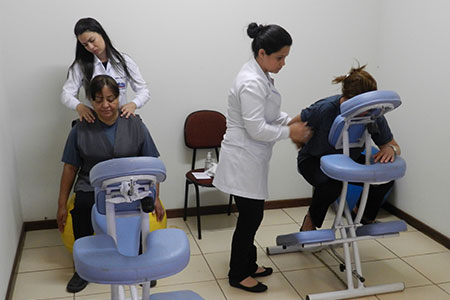 imagem mostra duas colaboradoras terceirizadas em cadeiras de massagem, sendo atendidas por fisioterapeutas