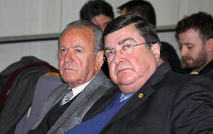 Fotografia em primeiro plano traz o ex-presidente do TRT-PR José Fernando Rosas e o ex-presidente nacional da OAB Roberto Busato na plateia da conferência