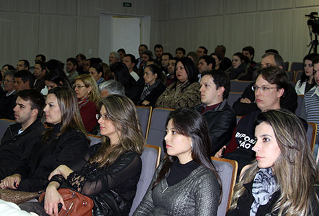 Fotografia em plano geral aberto traz a plateia do auditório ocupada pelos participantes