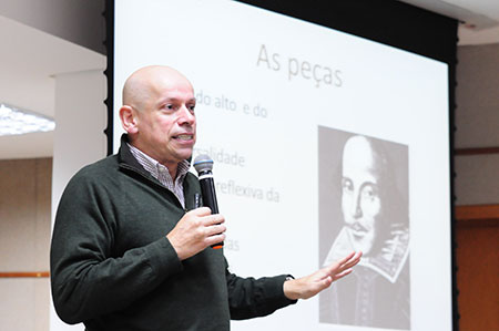 Professor Leandro Karnal, diante de tela, profere palestra.