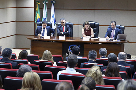 Mesa com autoridades participantes e plateia do evento