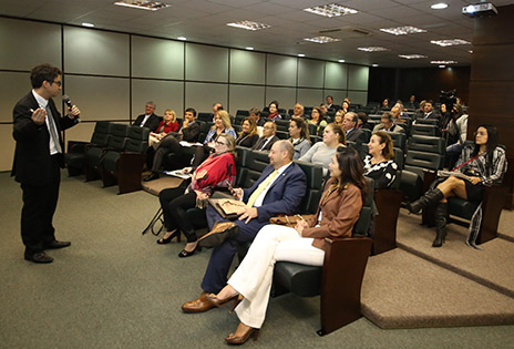 Imagem do auditório onde ocorreu o evento, com palestrante José Eduardo Romão e participantes.