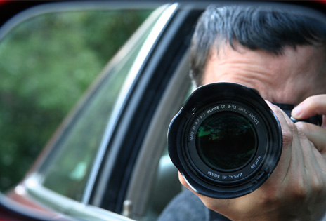 imagem fechada em retrovisor de um veiculo mostra um fotógrafo empunhando sua câmera
