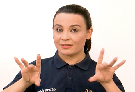 Imagem de intérprete de Libras, em plano médio, comunicando-se com as mãos