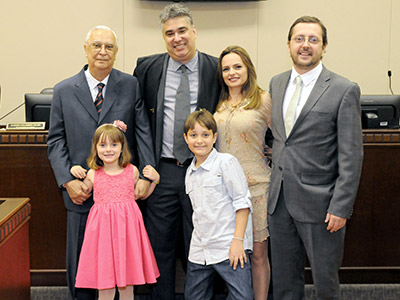 Imagem em plano aberto mostra o juiz Alexandre Augusto Campana Pinheiro posando junto de familiares (o pai, a esposa, os dois filhos e o seu cunhado). Todos olham para câmera e sorriem