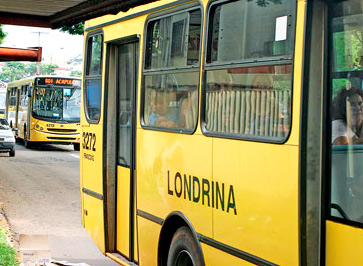 Imagem em plano médio mostra parcialmente a lateral de um ônibus com a inscrição 