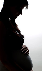 Imagem mostra silhueta de mulher grávida com uma das mãos sobre a barriga