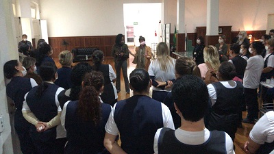 grupo de servidores terceirizados, com uniforme azul e branco, de costas para guias do centro de memória, em visitação à exposição