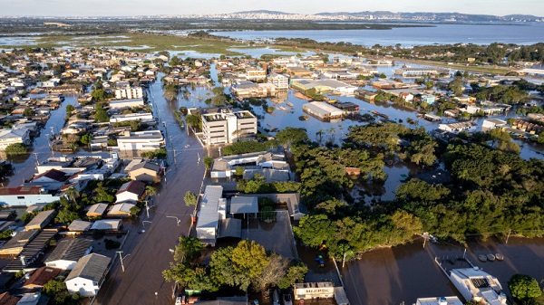 Imagem área mostra parte da cidade de Porto Alegre com ruas alagadas e a copa de árvores e o telhado de construção acima da linha dágua. 