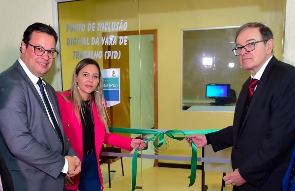 Fotografia da inaguração com descerramento de fita verde na porta do PID de Clevelândia. Do lado direito, o presidente do TRT-PR, desembargador Célio Waldraff. De outro, a prefeita de Clevelândia, Rafaela Losi. Ao lado dela, um advogado.
