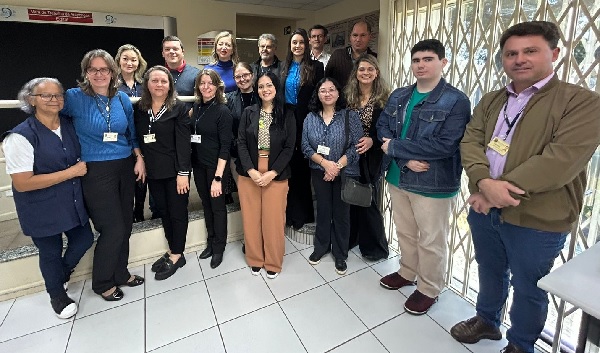 Fotografia de magistradas(os) e servidoras(es) da Vara do Trabalho de Arapongas. As pessoas estão em pé, lado a lado, em formato de semi círculo para posar para a fotografia. Há 11 mulheres e 6. homens.