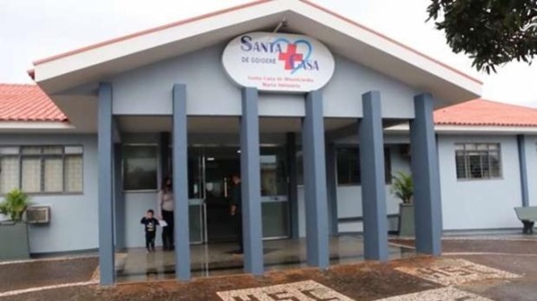 Fotografia da fachada da Santa Casa de Goioerê com um pórtico de cobertura com uma placa escrito 'santa casa' sustentado por seis colunas. Pintura em azul da fachada.