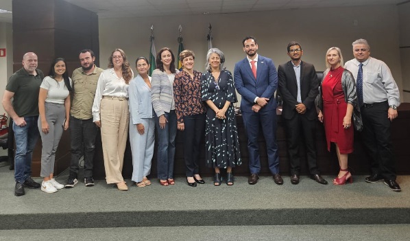 Grupo de 12 pessoas perfiladas lado a lado, sendo 7 mulheres e 5 homens.