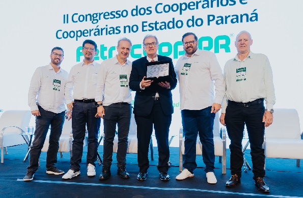 Seis pessoas perfiladas lado a lado. NO centro, o presidente do TRT-PR, de terno e gravata, Célio Waldraff, segura placa de homenagem