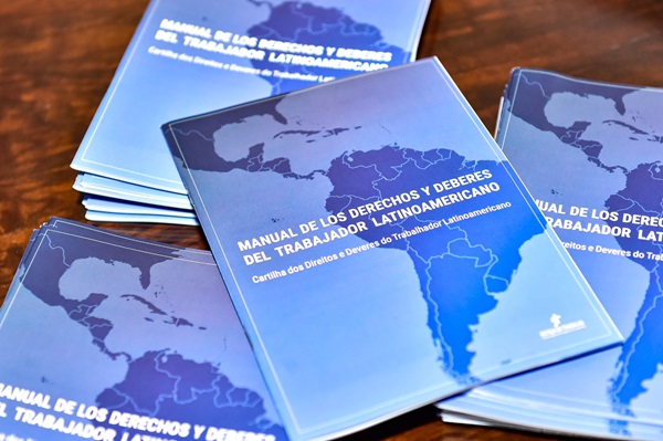 Fotografia de cartilhas sobre uma mesa, com capa prioritariamente azul com mapa da américa latona em destaque