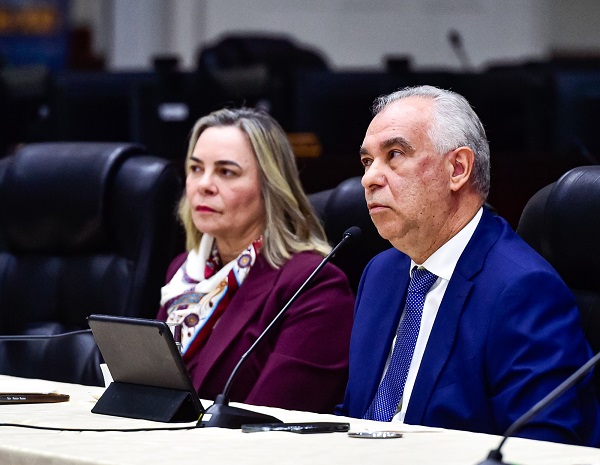 Fotografia de duas pessoas sentadas em poltronas em frente a uma mesa. Em destaque, o ministro Augusto Cezar, homem branco de cabelos grisalhos com terno azul. Ao fundo a ministro Katia Arruda, mulher branca de cabelos loiros e blusa roxa.