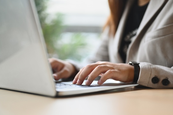 M&atilde;os de mulher em close-up digitando no teclado do laptop