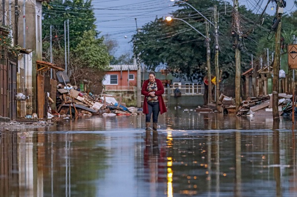 Mulher caminha entre destro&ccedil;os em &aacute;rea alagada pelas enchentes que atingiram o Rio Grande do Sul, em 2024.