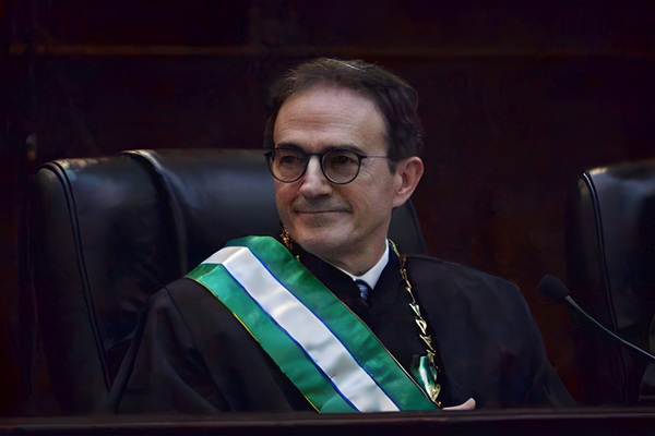 Fotografia do desembargador Arion Mazurkevic, homem branco de &oacute;culos e cabelos castanhos. Ele usa faixa verde e branca e colar de metal