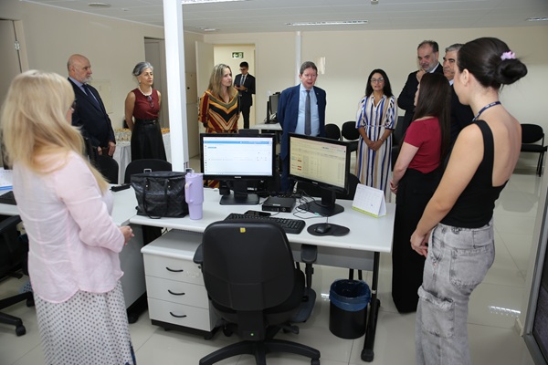 fotografia de dez pessoas conversando em torno de uma mesa com computadores, sendo seis mulheres e quatro homens
