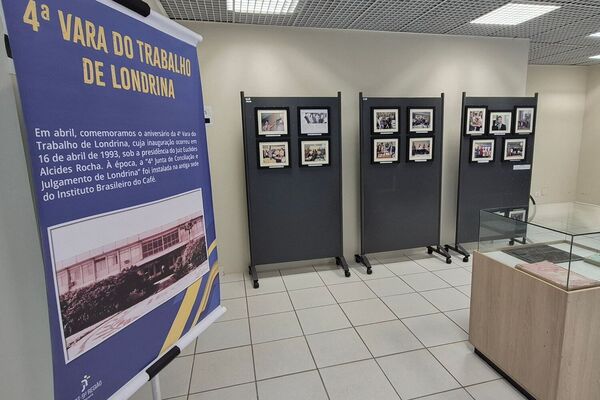 Imagem retrata a exposi&ccedil;&atilde;o comemorativa da cidade de Londrina, com um banner central, uma s&eacute;rie de biombos ao fundo e um expositor central.