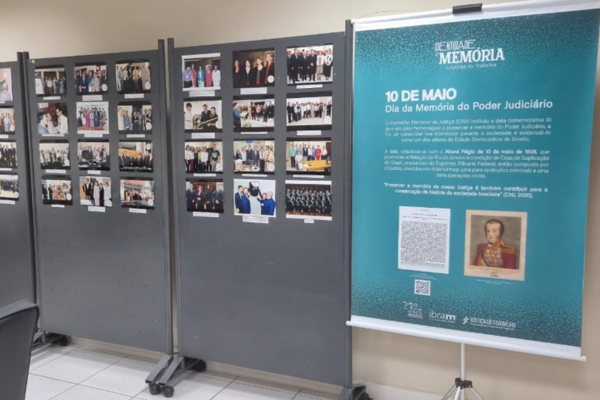 Imagem ilustrativa da exposi&ccedil;&atilde;o "Dia Nacional da Mem&oacute;ria do Poder Judici&aacute;rio", com um banner fotografias hist&oacute;ricas e contempor&acirc;neas das unidades judici&aacute;rias do TRT-PR, no F&oacute;rum de Londrina.