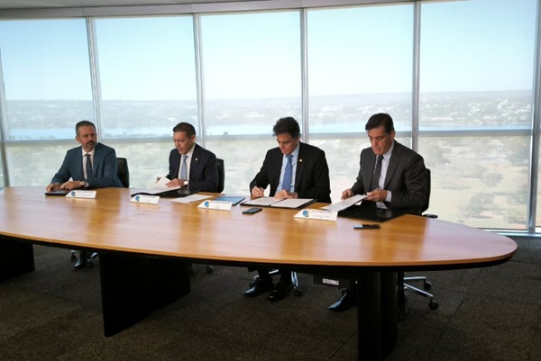 Ministros e procurador, &agrave; mesa, assinam acordo de coopera&ccedil;&atilde;o. Ao fundo, janelas de vidro