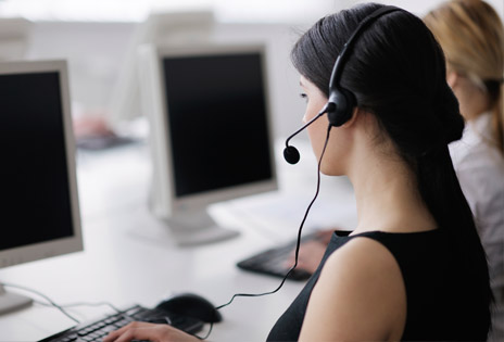 imagem fechada mostra atendente de telemarketing com fones de ouvido diante de uma tela de computador 