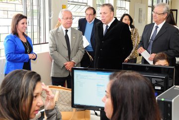 Imagem em plano aberto mostra o corregedor-geral da Justiça do Trabalho, ministro João Batista Brito Pereira em visita ao Projeto Horizontes. O ministro observa acadêmicos de Direito que participam do projeto enquanto estes acessam informações nos computadores. O corregedor-geral está acompanhado do presidente do TRT-PR, Altino Pedrozo dos Santos, dos desembargadores Cássio Colombo Filho e Célio Horst Waldraff, e da diretora do arquivo-geral, Neide Spindola